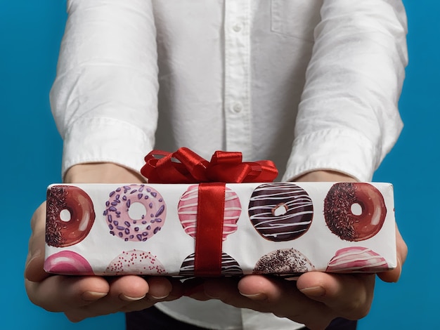 Cerca de joven en una camisa blanca da regalo