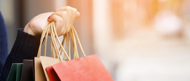 Cerca de una joven consumista sosteniendo de la mano muchas bolsas de compras en una boutique de moda después de comprar regalos mientras caminaba por la calle con espacio para copiar disfrutando de la venta de verano y el concepto de personas