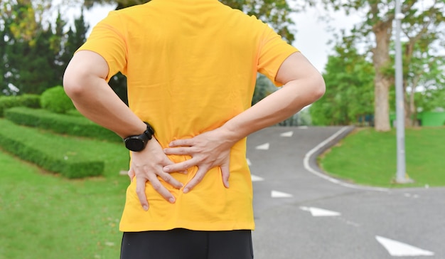 Cerca del joven deportista asiático tiene dolor en los músculos y las articulaciones durante el ejercicio al aire libre, durante el entrenamiento o correr y el concepto de deporte injuty