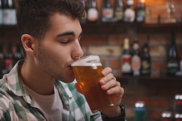 Cerca de un joven disfrutando de beber una deliciosa cerveza en el pub