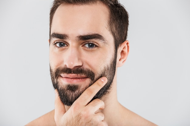 Cerca de un joven guapo sin camisa barbudo que se encuentran aisladas sobre blanco