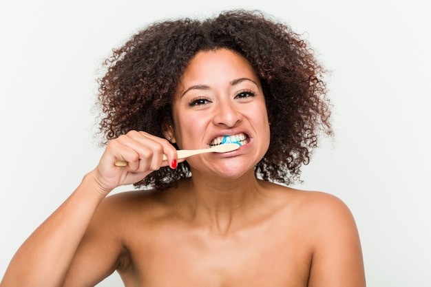 Cerca de una joven mujer afroamericana cepillarse los dientes con un cepillo de dientes