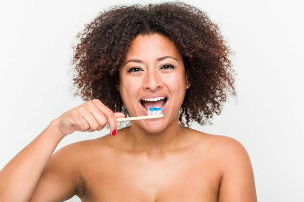 Cerca de una joven mujer afroamericana cepillarse los dientes con un cepillo de dientes