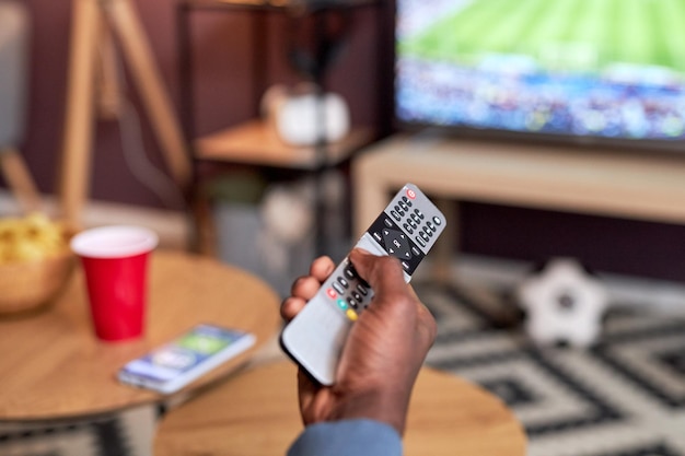 Foto cerca de un joven negro viendo un partido de fútbol en casa