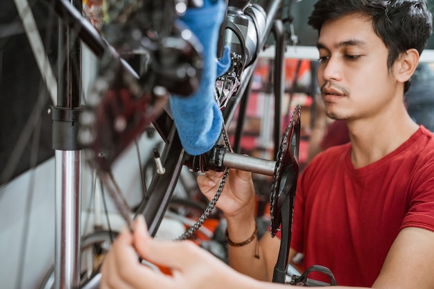 Cerca de un joven en rojo trabajando cuidadosamente instalando cadena de bicicleta