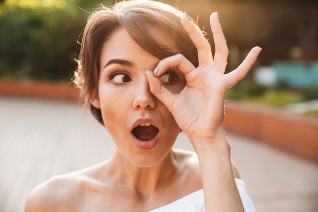 Cerca de una joven sorprendida mostrando gesto ok