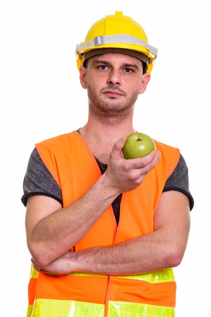 Cerca de joven trabajador de la construcción con manzana verde