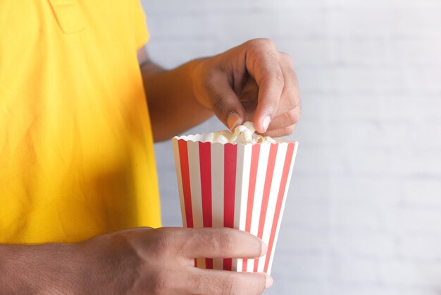 Cerca de joven en traje casual comiendo palomitas de maíz.