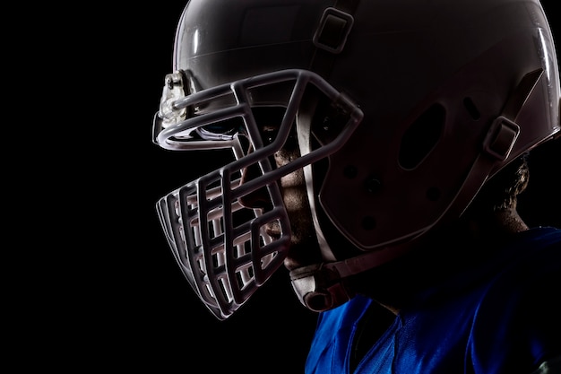 Cerca de un jugador de fútbol con un uniforme azul sobre una pared negra