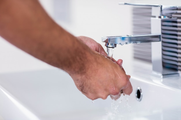 Cerca de lavarse las manos con jabón bajo el chorro de agua en el lavabo del baño