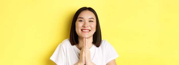 Cerca de linda mujer asiática diciendo gracias y sonriendo tomados de la mano en namaste orar gesto stan