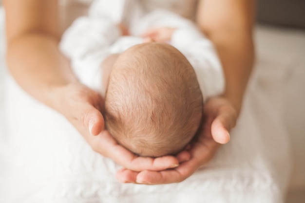 De cerca. Lindo bebé recién nacido durmiendo en brazos de la madre. Maternidad.