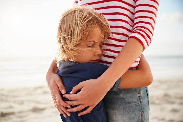 Cerca de madre abrazando a hijo en vacaciones de verano en la playa