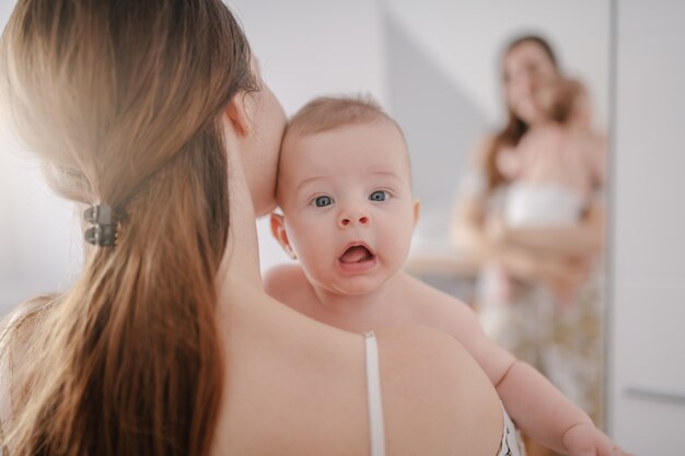 Cerca de la madre caucásica sosteniendo a su amoroso hijo de seis meses.