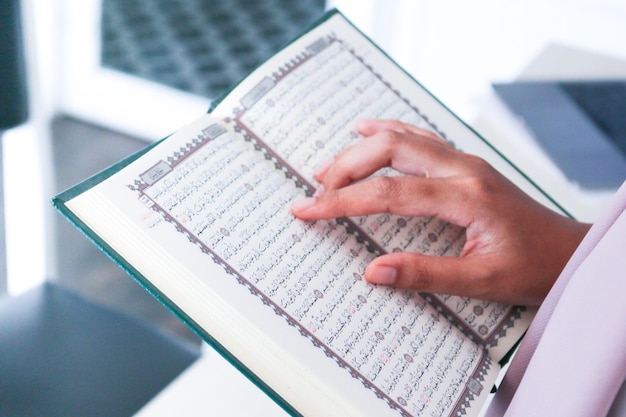 Cerca de la mano al leer el Sagrado Corán en la mezquita Enfoque selectivo