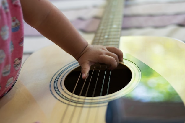 Cerca de la mano del bebé tocando la guitarra