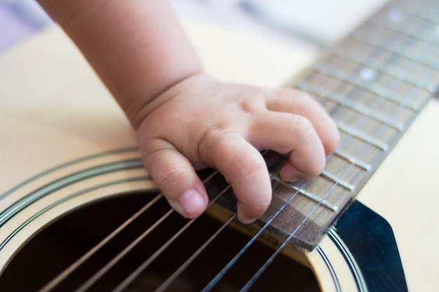 Cerca de la mano del bebé tocando la guitarra