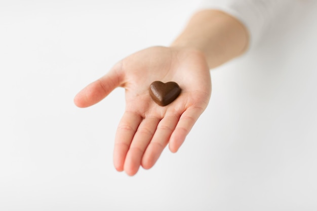 cerca de la mano con caramelos de chocolate en forma de corazón