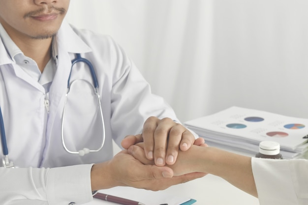 Foto cerca de la mano del doctor tranquilizando a su paciente en el hospital doctor tomados de la mano del paciente