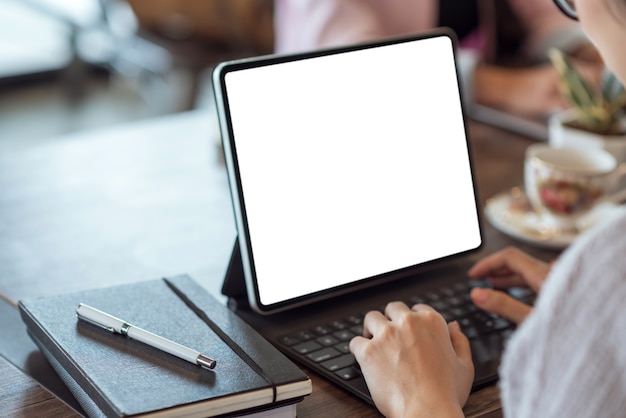 Cerca de la mano de la empresaria mediante tableta digital en pantalla blanca en la mesa