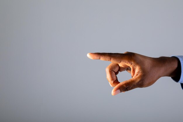 Cerca de la mano del empresario tocando la pantalla invisible contra el fondo gris