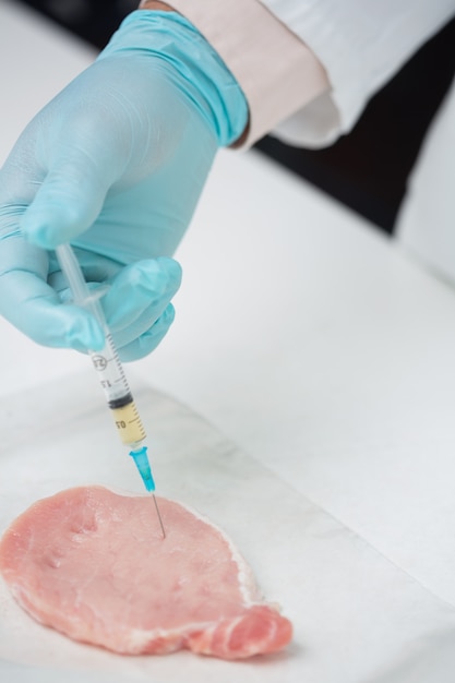 Cerca de una mano enguantada de los investigadores que inyecta la carne