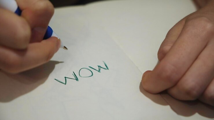 Foto cerca de la mano escribiendo palabras en papel blanco con un bolígrafo concepto niño está escribiendo una palabra madre en un