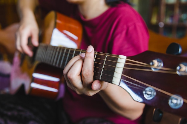 Cerca de la mano femenina tocando la guitarra.