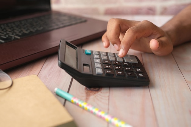 Cerca de la mano del hombre con calculadora