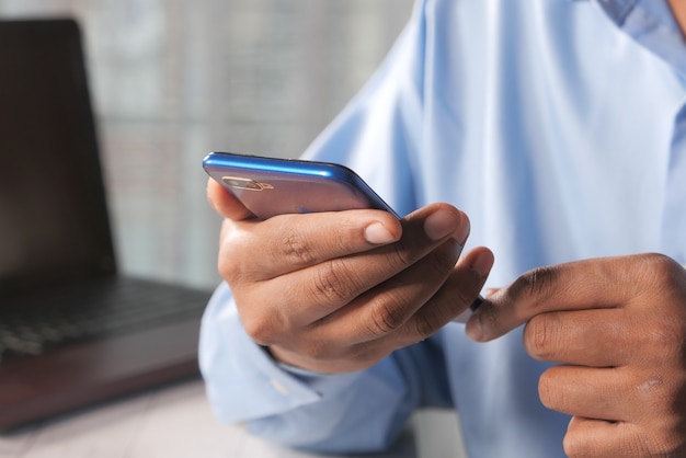 Cerca de la mano del hombre joven con teléfono inteligente.