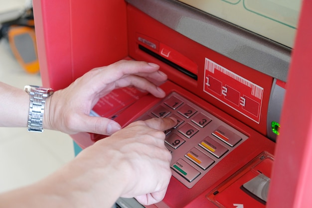 Cerca de la mano del hombre que ingresa el pin o la contraseña en el teclado del cajero automático para la transacción