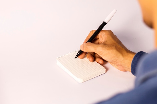 de cerca de la mano de un hombre que sostiene un marcador escribiendo en un cuaderno vacío alineado negocios de educación y conceptos de auto-desarrollo