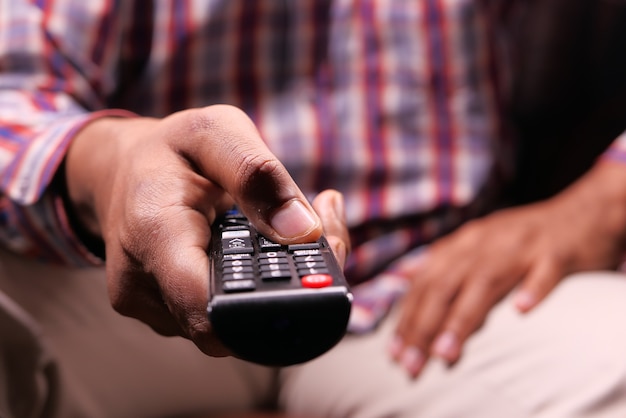 Cerca de la mano del hombre sosteniendo el control remoto de la televisión.