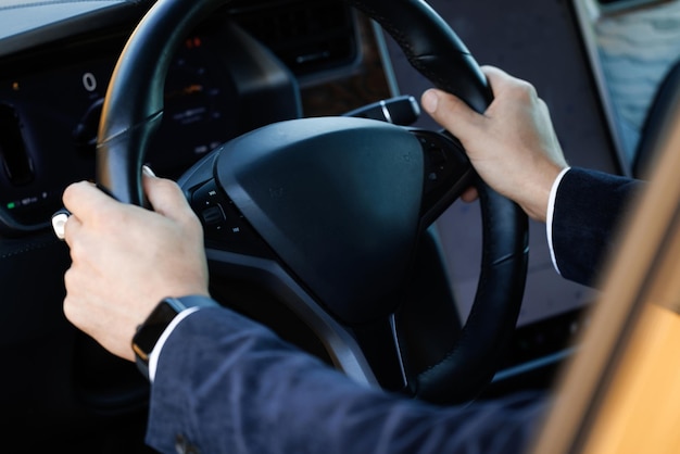 Cerca de la mano del hombre en el volante del vehículo mientras conduce un hombre conduciendo un automóvil en la carretera