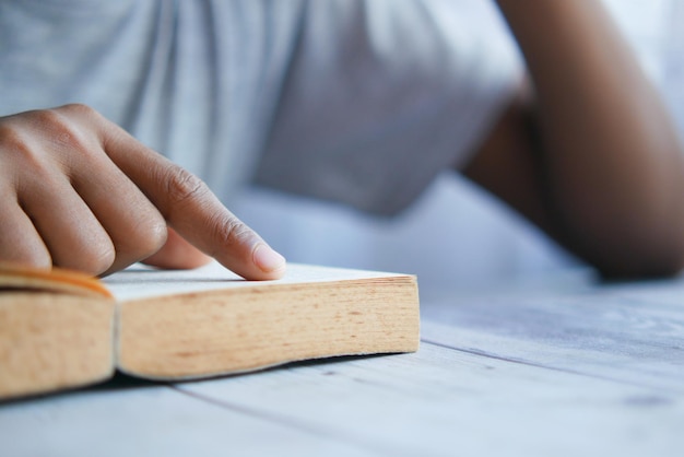 Cerca de la mano del joven leyendo un libro