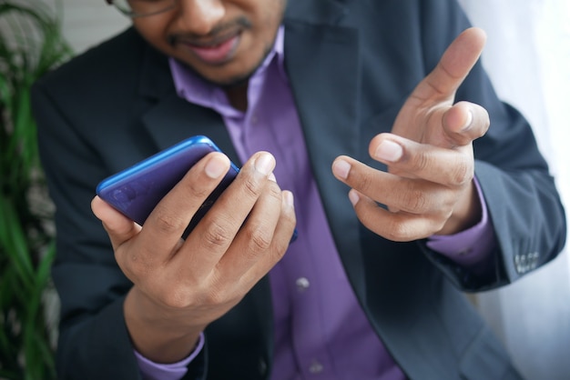 Cerca de la mano del joven con teléfonos inteligentes.