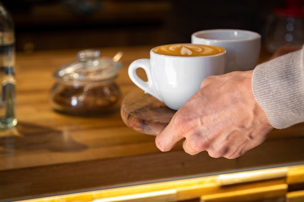 Cerca de la mano masculina tomando una taza de café caliente