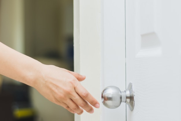 cerca de la mano de la mujer llegando a la perilla de la puerta, abriendo la puerta