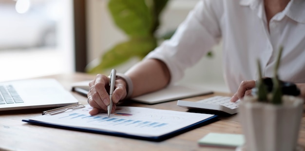 Cerca de la mano mujer de negocios trabajo datos documento gráfico gráfico informe marketing investigación desarrollo planificación gestión estrategia análisis concepto financiero y contable.