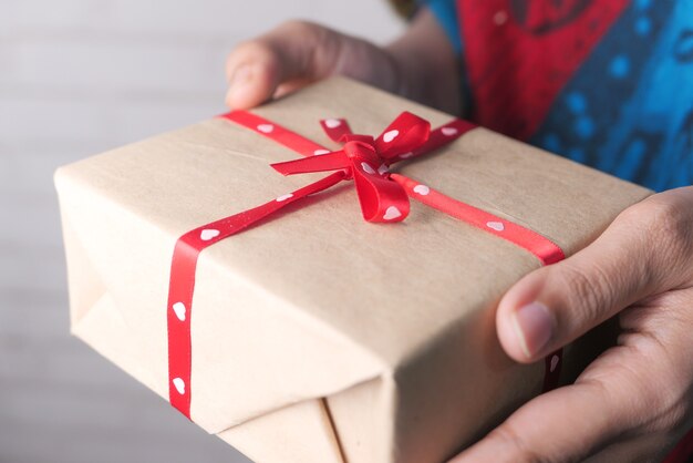 Cerca de la mano de la mujer sosteniendo una caja de regalo