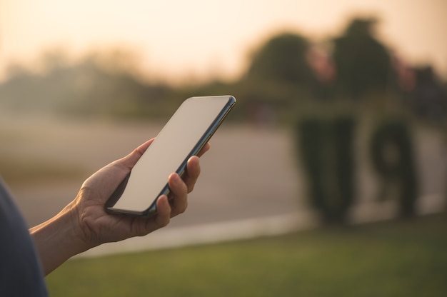 Cerca de la mano de la mujer sosteniendo y usando el teléfono inteligente para redes sociales, mensajería o compras en línea. Gente feliz con concepto de negocio de tecnología.