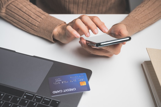 Cerca de la mano de la mujer con teléfono celular o móvil para comprar en línea o pagar con tarjeta de crédito. Concepto de compras en línea.