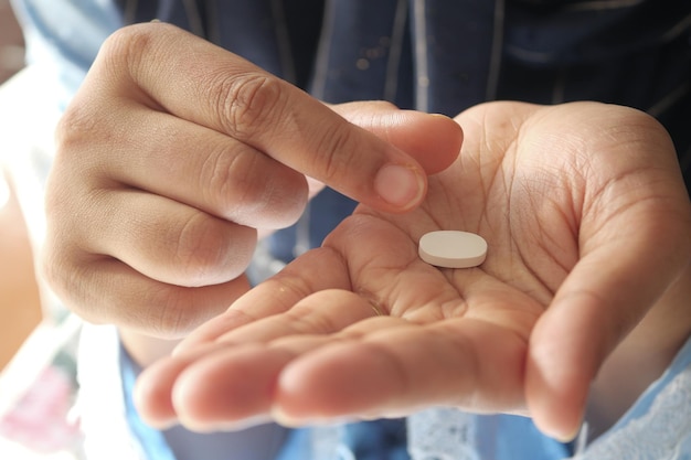 Cerca de la mano de la mujer tomando pastillas