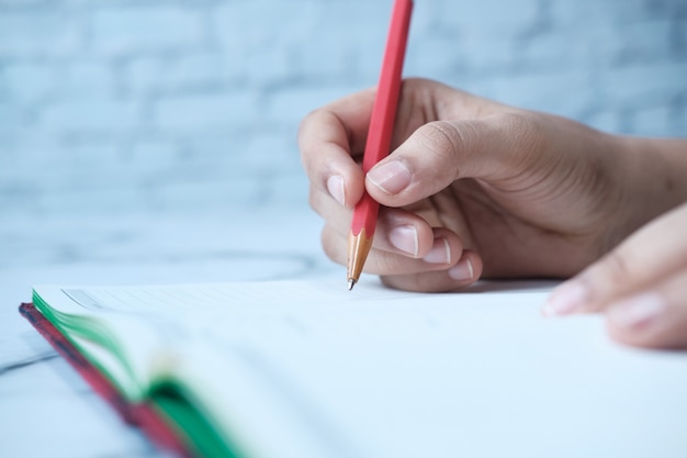 Cerca de la mano de las mujeres escribiendo en el Bloc de notas.