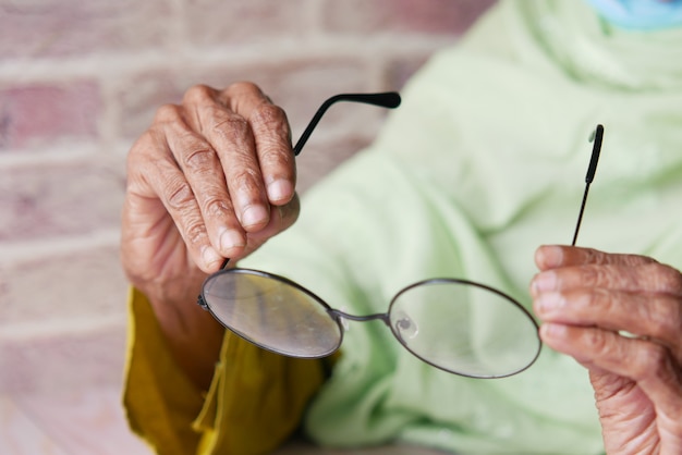 Foto cerca de la mano de las mujeres mayores sosteniendo anteojos viejos