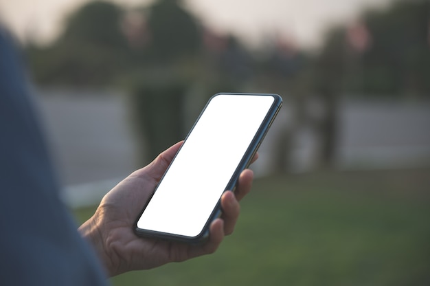 Cerca de la mano de las mujeres y usar el teléfono inteligente al aire libre