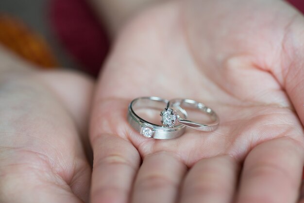 Cerca de una mano sujetando dos anillos de boda de plata