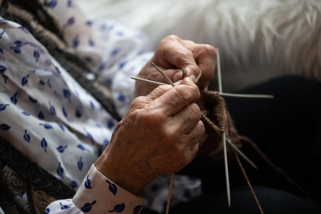 Cerca de las manos de una anciana tejiendo calcetín