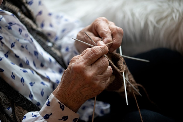 Cerca de las manos de una anciana tejiendo calcetín