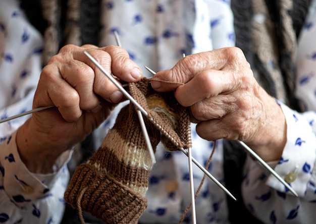 Cerca de las manos de una anciana tejiendo calcetín